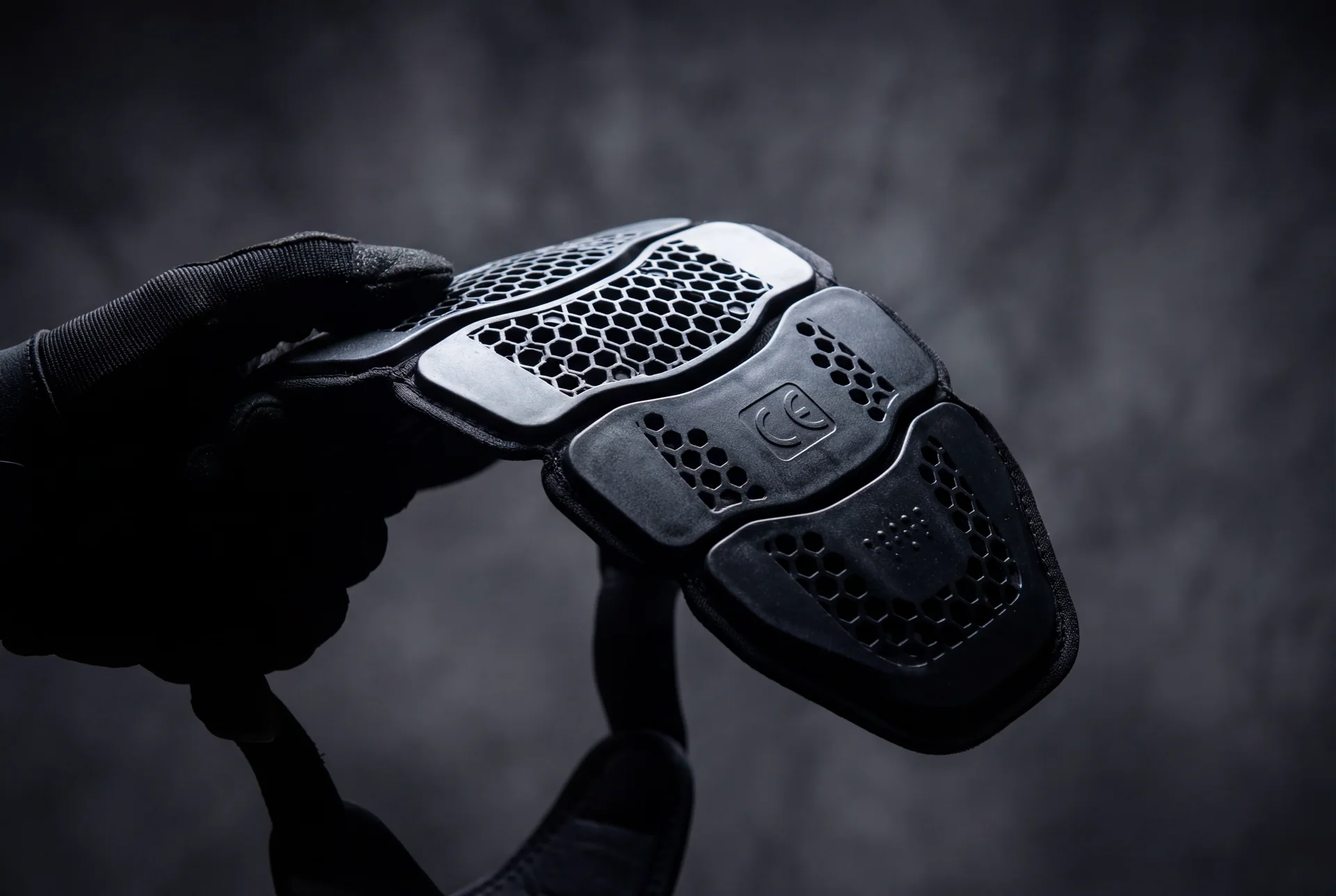 Protecciones CE de moto nivel 2 D3O espaldera y rodilleras sobre superficie oscura con iluminacion dramatica